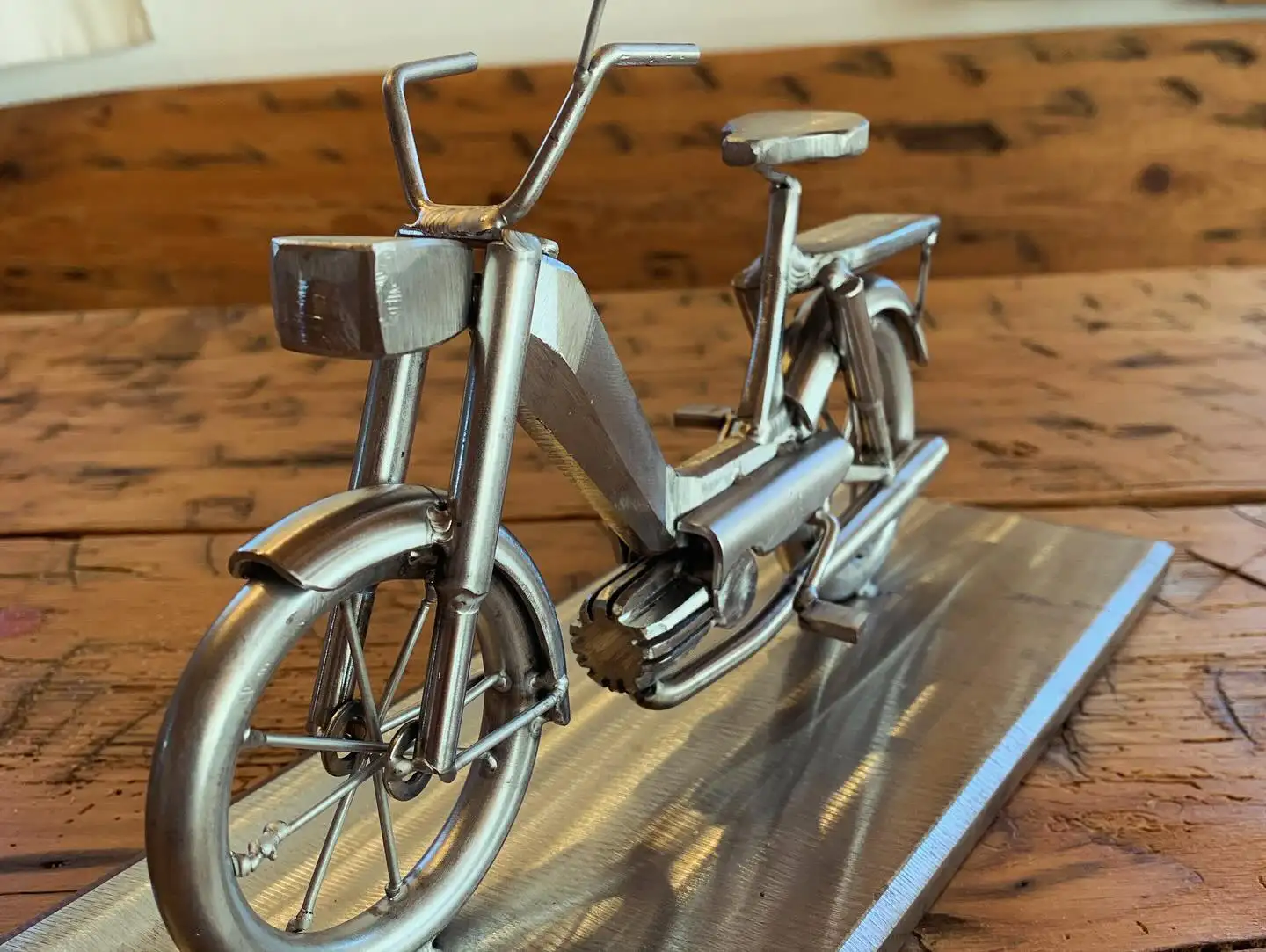 Fertige Metallskulptur eines Mopeds auf einer Stahlplatte