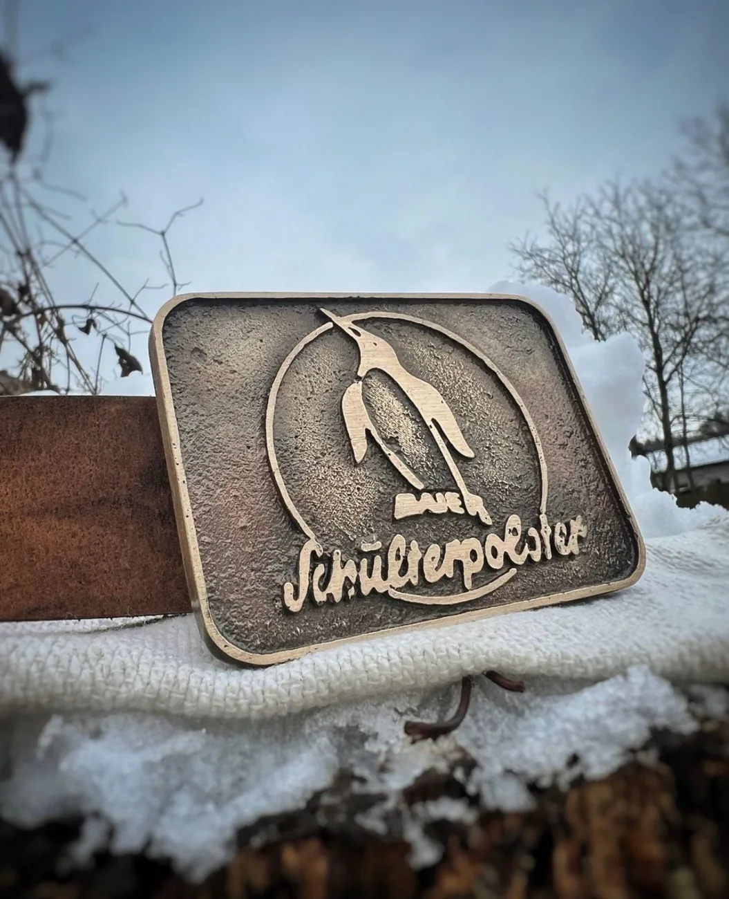 Rechteckige Gürtelschnalle mit Motiv und Schriftzug im Schnee