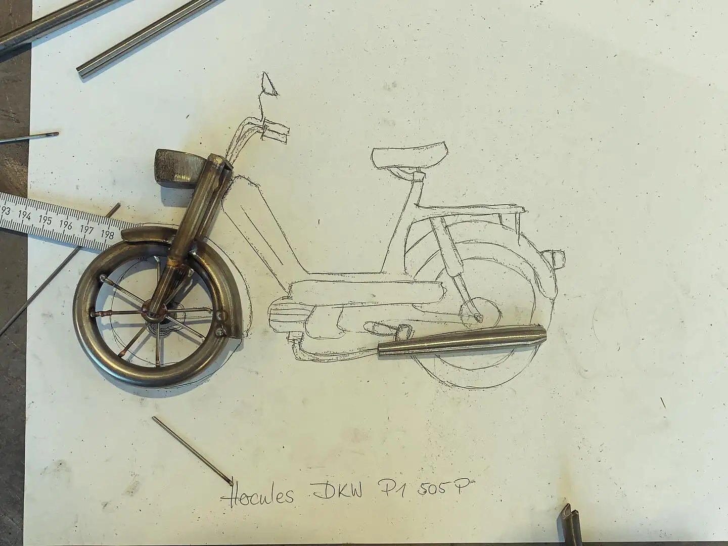 Bleistiftskizze eines Mopeds, daneben die ersten gebogenen Metallteile